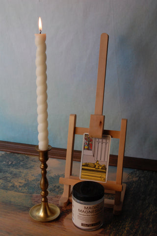 Jar of "Magic Magnesium" next to easel with tarot card and candle stick.