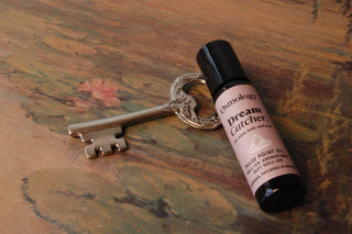 Roller of Dream Catcher Pulse Point Oil on top of a decorative key.