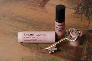 Osmology Pulse Point Oil with its packaging and a decorative key on top of a painting.
