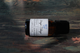Blue Sage Deep Sleep Essential Oil bottle laid sideways on a painting.