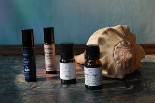 A bottle of 100% pure lavender essential oil styled next to other oils and a seashell.