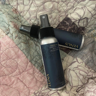 Two bottles of  Magna Dea's' Venus' and 'Luna' on a patterned quilt background