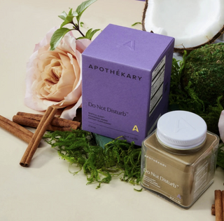 "Do Not Disturb" by Apothékary, is a powdered blend of herbs with the intention to help you reach deeper sleep. Here the purple packing is shown next to the jar and presented with floral and herbal elements. 